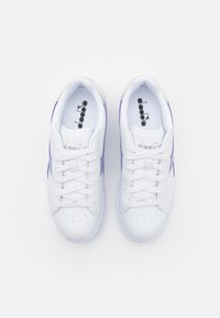 Sneakers bianchi con accenti viola, realizzati in materiale sintetico liscio. Le caratteristiche includono punta tonda, design con lacci e dettagli perforati.