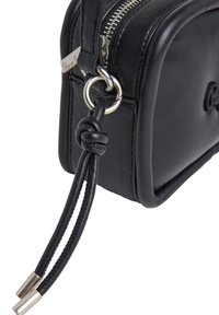 Sac en cuir noir de forme rectangulaire, doté d'une fermeture éclair argentée, d'un anneau en métal et de poignées en cuir tressé avec des accents argentés.