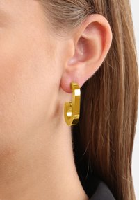Guldtonad hoop-örhänge med rektangulär design, polerad yta och slät textur, bärs i örat.