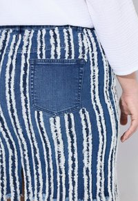Gonna in denim con una fantasia a righe sfrangiate in blu e bianco. Caratterizzata da una tasca posteriore e orlo grezzo. Il materiale è morbido con una finitura testurizzata.