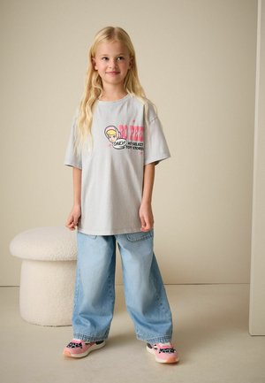 Light gray short-sleeve t-shirt with a graphic print, paired with loose light blue denim jeans and pink sneakers with a black pattern.