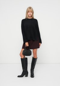 Pull noir en peluche, jupe bordeaux, bottes noires jusqu'au genou avec un talon bloc et un sac à main noir texturé. Design simple, palette de couleurs élégante.