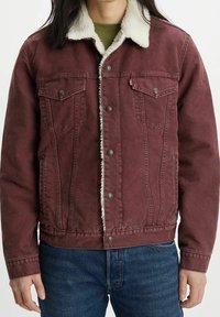 Burgundy denimjacka med en vit shearlingkrage, med två bröstfickor, knäppning med knappar och ribbade cuffs. En varm, texturerad design.