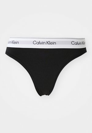 Zwarte katoenen string met een witte elastische tailleband met "Calvin Klein" branding. Gladde textuur, minimalistisch ontwerp.