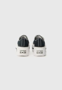 Black canvas sneakers with a low-top design, white rubber soles, and contrasting stitching. Features "Converse All Star" branding on the back.