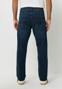 Dunkelblaue Jeans aus Denim mit geradem Schnitt, ausgestattet mit Gesäßtaschen mit nahtdetails und einem kontrastierenden braunen Lederpatch am Bund.