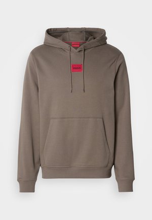 Sweatshirt à capuche dans une couleur brune discrète, doté d'une poche avant et d'une étiquette rouge avec "HUGO" sur la poitrine. Texture lisse et design décontracté.