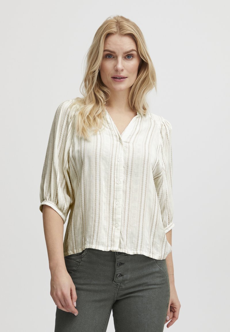 Blusa abotonada en color crema claro con rayas verticales, hecha de una tela suave. Presenta un escote en V y mangas abullonadas de tres cuartos.