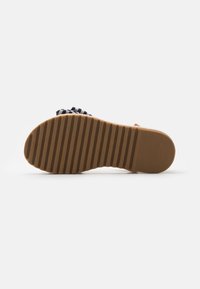 Casualowy but z gumową podeszwą i materiałową cholewką w paski w kolorach granatowym i białym, z teksturowaną podeszwą zapewniającą przyczepność i stabilność.