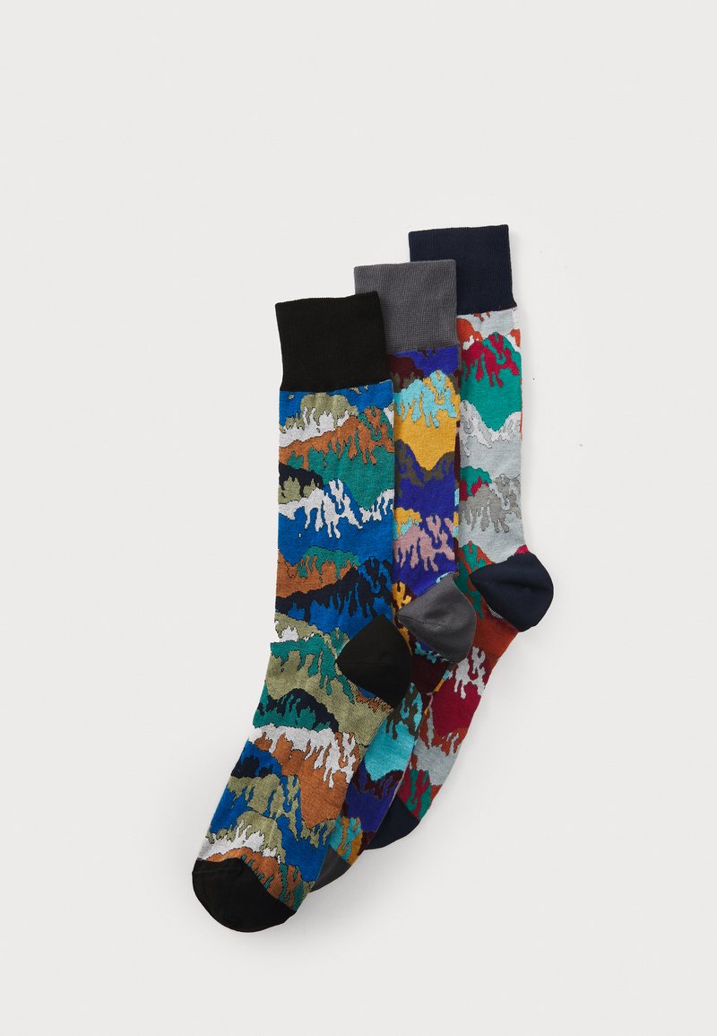 Tre paia di calzini a fantasia: uno multicolore con motivi ondulati, uno grigio e uno blu navy, ciascuno con risvolti e punte nere a contrasto.