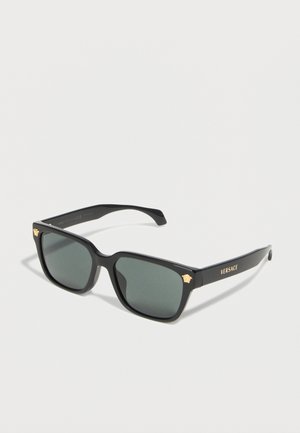Lunettes de soleil rectangulaires noires Versace avec verres foncés, logo Méduse doré aux coins et marquage Versace sur les branches.