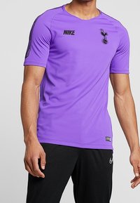Purple Nike sports jersey features short sleeves, a crew neck, and black Tottenham Hotspur logo on the chest, with accent stripes on the shoulders.