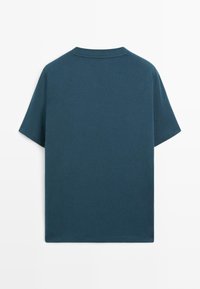 T-shirt a manica corta in cotone verde petrolio scuro, con orlo dritto e scollo rotondo. Tessuto liscio senza motivi o dettagli visibili.
