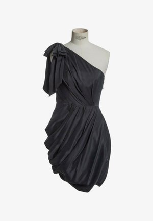 Vestido negro de satén con un solo hombro, con tela drapeada y fruncida y un lazo sobredimensionado en el hombro, exhibido en un maniquí.