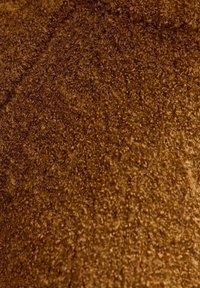 Tela texturizada marrón con una superficie suave y peluda, que exhibe un tono rico y cálido y una apariencia densa y mullida.