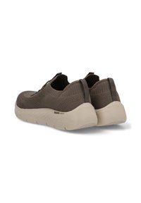 Zapatos ligeros de color marrón oscuro tipo slip-on con un upper de punto texturizado y una suela blanca flexible, que cuentan con tiradores para ponerlos y quitarlos fácilmente.