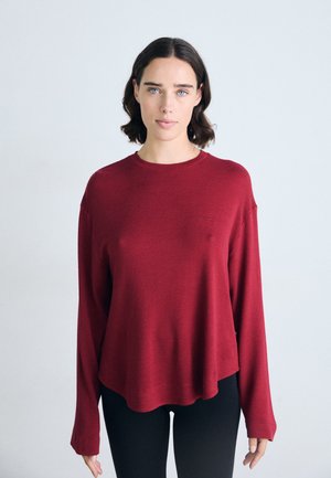 Camicia bordeaux a maniche lunghe con una texture a costine, scollatura tonda e vestibilità comoda, caratterizzata da un piccolo logo sul petto.