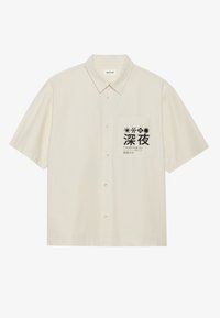 Cămașă cu mânecă scurtă, din bumbac bej deschis, cu un buzunar pe piept ce prezintă text în japoneză neagră și accente grafice.