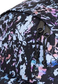 Zaino in tessuto nero con motivo astratto colorato e dettagli rosa e blu. Include due cerniere con tiralampo a cordoncino.