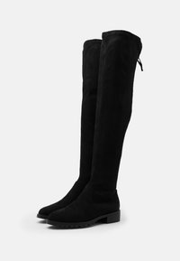 Black over-the-knee boots made from suede, featuring a rounded toe, low block heel, and smooth texture with a pull tab at the top.