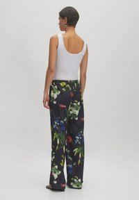 Bloemen brede broek met een zwarte achtergrond en levendige groene, rode en blauwe bloemen, elastische tailleband en een zachte stoftextuur.