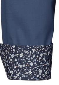 Pantaloni blu navy con un risvolto a fantasia floreale in tonalità di blu, bianco e marrone, caratterizzati da una texture liscia e una vestibilità su misura.