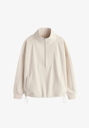 Cream-colored pullover with a high collar, half-zip front, side pockets, and adjustable drawstring at the hem. Smooth texture and relaxed fit.