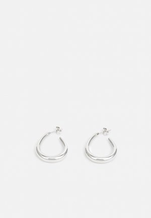Paire de petites boucles d’oreilles anneaux épaisses en argent avec extrémités ouvertes et fermoir papillon sur fond blanc.