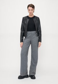 Svart skinn bomberjakke, tettsittende svart topp, rutete grå vide bukser og kraftige svarte platåstøvler. Glatt tekstur, skreddersydd design.