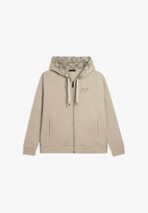 Hoodie zippé beige clair avec une doublure de capuche à motif, des poches frontales, des cordons de serrage ajustables et un petit logo sur la poitrine.