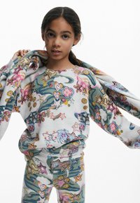 Bunt gemusterter Pullover und Hose in Grau, die whimsical Designs von Blumen, Sternen und Schmetterlingen in lebhaftem Pink, Blau und Grün zeigen.