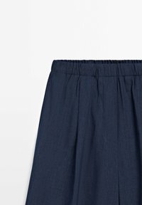 Pantalon avec ceinture élastique bleu marine et plis subtils, fabriqué en tissu léger texturé.