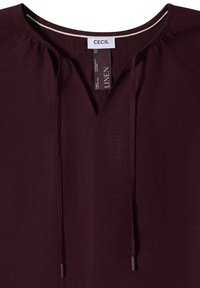 Blusa in lino viola scuro con scollo tondo, dettaglio in tessuto arricciato e coulisse frontali, con etichetta del marchio CECIL.
