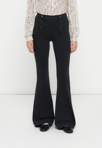 Pantalons évasés noirs taille haute avec quatre boutons décoratifs sur les poches avant. Tissu lisse avec une coupe structurée et un large ourlet.