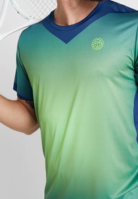 Sportovní tričko s gradientem zelené a modré barvy, v-výstřih, krátké rukávy a tkanina odváděj ící vlhkost s perforovanou strukturou.