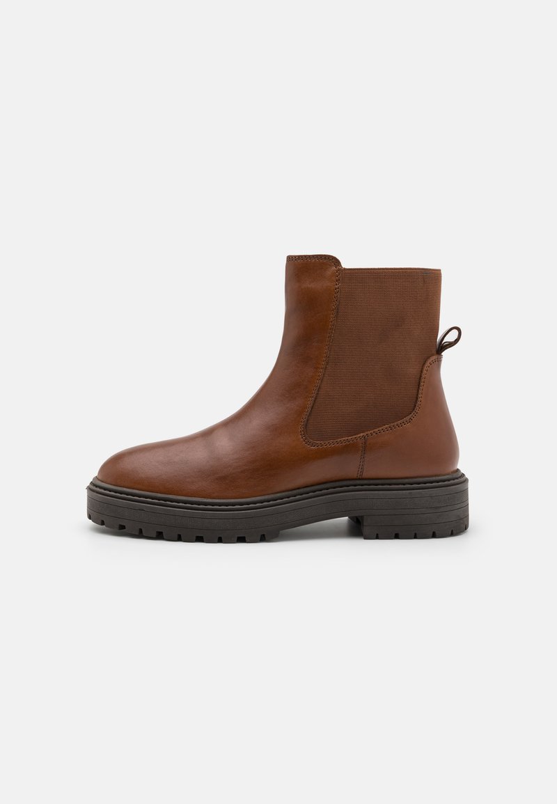Botine de piele maro până la glezne, cu panouri elastice laterale, un tab de prindere și o talpă groasă din cauciuc cu un model texturat.