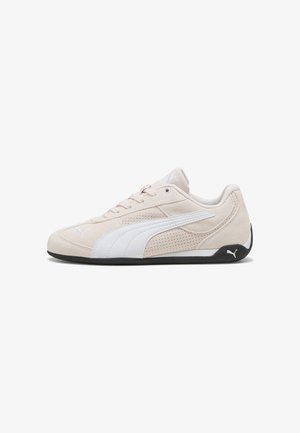 Lichtbeige suède sneaker met witte accenten, geperforeerde details en zwarte rubberen buitenzool. Vetersluiting en gevoerde kraag.