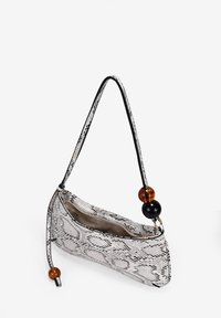Bolso hobo en estampado de serpiente blanco y negro, con una textura suave, correa negra y dos cuentas decorativas en ámbar y negro.