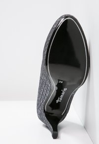 Chaussure à talon noire avec une tige texturée, semelle noire brillante et bout pointu. Taille indiquée comme 39. Présente un motif en diamant subtil sur le tissu.