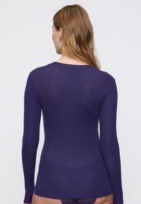 Lange mouwen top in donkerpaars geribd stof met een ronde halslijn en een aansluitend ontwerp, met een gladde textuur en minimale details.
