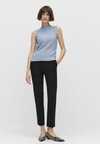 Vaaleansininen ribattuja olkaimia vailla oleva toppi yhdistettynä mustiin räätälöityihin housuihin ja käärmeennahkakuosisilla mokkasiineilla. Minimalistinen muotoilu, sileä materiaali, hyvin muotoiltu istuvuus.