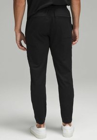Sorte joggerbukser med elastisk talje, sidelommer og en slim fit. Fremstillet af let materiale med en glat tekstur.