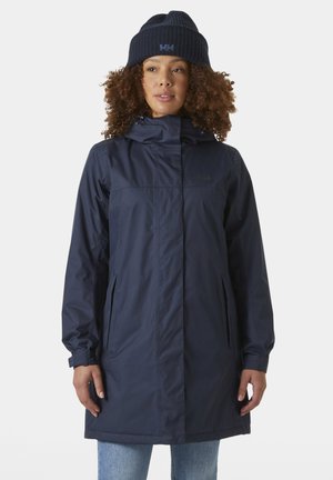 Navy waterproof coat with a hood, featuring a front zipper, two side pockets, and a relaxed fit, paired with a matching knitted beanie.