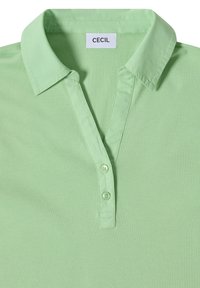 Polo vert clair avec col et deux boutons sur le devant, avec une étiquette de marque "CECIL" à l'intérieur de l'encolure.