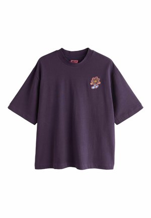 Lilla lühikeste varrukatega T-särk ümmarguse kaelusega, vasakul rinnal väike värvikas tikandiga naeratava lillega, kellel on sinised jalad.