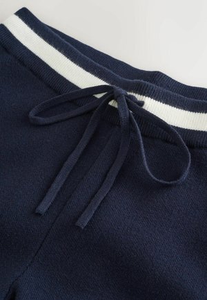Marineblaue Jogginghose mit einem elastischen Bund in Weiß und Marineblau, ausgestattet mit einem Kordelzug und aus weichem, strukturiertem Material.