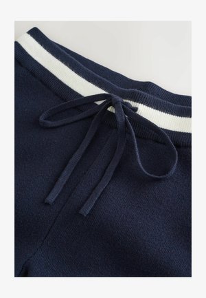 Marineblaue Jogginghose mit einem elastischen Bund in Weiß und Marineblau, ausgestattet mit einem Kordelzug und aus weichem, strukturiertem Material.
