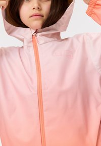 Veste légère à capuche dégradée de rose clair à corail, dotée d'une fermeture éclair à l'avant et d'un logo discret sur la poitrine.