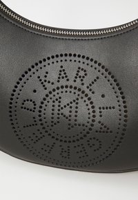 Sac à main en cuir noir avec un design de logo de marque perforé. Forme arrondie avec fermeture éclair et détails de surface texturée.
