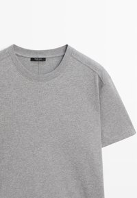 Szary t-shirt z krótkim rękawem, wykonany z miękkiej mieszanki bawełny. Posiada okrągły dekolt oraz lekko przesunięte szwy na ramionach. Metka widoczna wewnątrz dekoltu.
